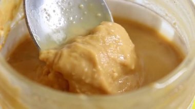 Kavanozda bir kaşık fıstık ezmesiyle karıştır. Sağlıklı yiyecekler. Yakın çekim, seçici çekim.