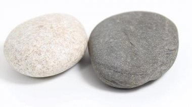 Beyaz arka planda iki pürüzsüz deniz taşı. Döner masa. Seçici odak.