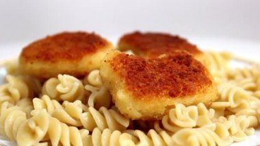 Üzerine ketçap dökülmüş bir tabak makarna ve tavuk nugget. Yakın çekim, seçici odaklanma.