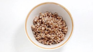 Beyaz arka planda kaynamış karabuğday tabağı. Basit ve etkili karabuğday diyeti. Yukarıdan görünüşü.