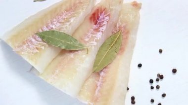 Çiğ pollock fileto üzerine tuz, biber ve defne yaprağı serpiştirilmiş. Üst görünüm, seçici çekim.