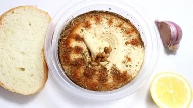 Arkaplanda beyaz ekmek, sarımsak ve limonlu bir tabakta humus. Orta Doğu 'dan geleneksel bir aperatif. Yukarıdan görünüşü.