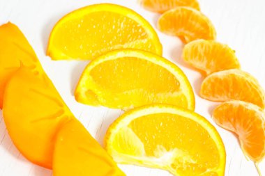 Beyaz arka planda dilimlenmiş mandalina, portakal ve hurma dilimleri. Seçici atış.