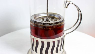 Beyaz arka planda, cam bir Fransız pres makinesinde demlenmiş çay. Kapat..