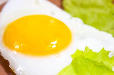 Yağda yumurta ve yeşil marul yaprakları. Yakın çekim, seçici çekim.