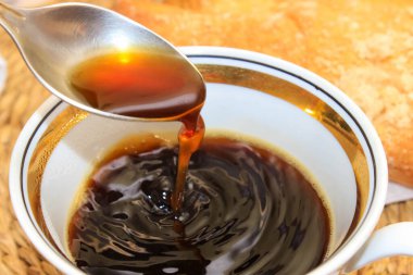 Bir fincan sade kahve, sıcak bir içeceğin kaşıkla soğutulduğu yer. Yakın çekim, seçici çekim.