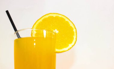 Bardakta portakal kokteyli, pipet ve bir dilim portakal. Yakın çekim, seçici odaklanma.