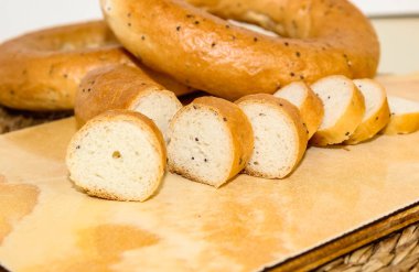 Arka planda beyaz kupa olan haşhaş tohumlu simit. Seçici odak.