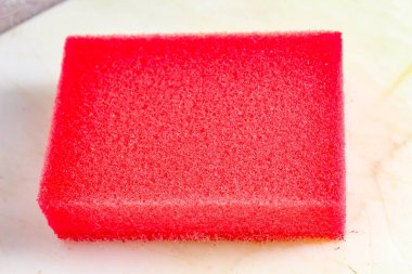 Açık arkaplanda kırmızı renkli ev süngeri. Yakın plan..