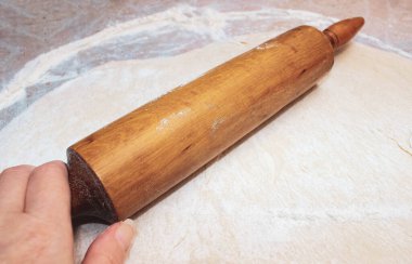 El, hamuru yuvarlayan bir oklava tutar. Yakın çekim, seçici çekim.