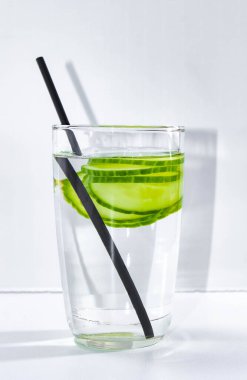 İçmek için kamışla birlikte dilimlenmiş salatalıkla detoks suyu. Kilo verme ve vücudu temizleme kavramı. dikey çerçeve. Yakın çekim, seçici çekim.