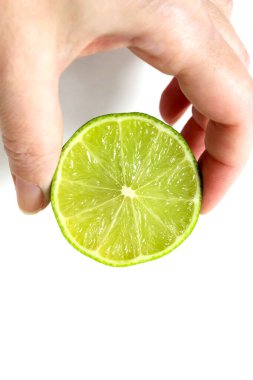 Bir kadının eli arka planda parmaklarıyla yarım bir limonu tutuyor. Sağlıklı beslenme kavramı. Dikey çerçeve.