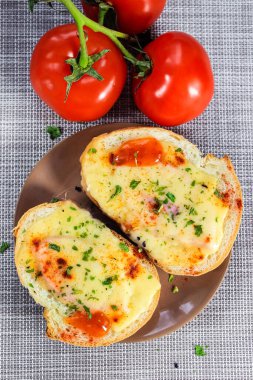Sandwiches with melted cheese on a plate with tomatoes. Top view.