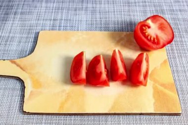 Stopmotion video. Cut fresh tomatoes into slices on a cutting board. Close-up, selective shot.