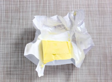 Masanın üzerinde açık bir paket tereyağı var. Üst görünüm.