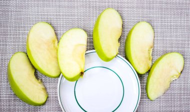 Yeşil elma dilimleri çay tabağının yanına konur. Beslenme, detoks. Üst görünüm.