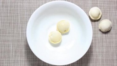 Hareket animasyonunu durdur. Çiğ hamur köfteleri sırayla beyaz bir tabağa atlıyor. Üst görünüm.