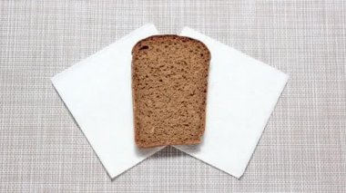 Hareket animasyonunu durdur. Baharatlı ketçapın yayıldığı ve sonra parçaların koparıldığı bir parça siyah ekmek. Üst görünüm.