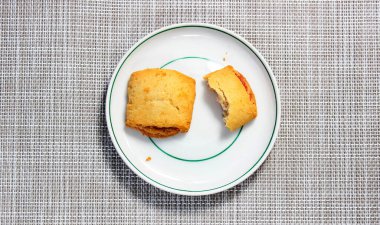 Bir fincan tabağında tam ve ısırılmış kurabiye. Üst görünüm.