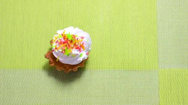 停止动作动画 带有奶油和彩色洒水的蛋糕篮在绿色背景上移动 顶部视图 — 图库视频影像