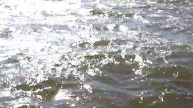 Rezervuarın bulanık videosu, suda dalgalar, güneşten gelen parıltı. Arka plan. Yakın plan..