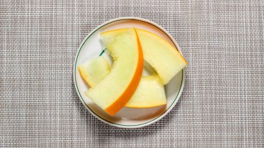 Bir tabak üzerinde dilimlenmiş olgun kavun parçaları. Sağlıklı bir tatlı. Üst görünüm.