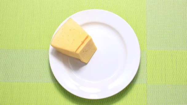 停止动作动画 硬奶酪 切碎在盘子上移动 芝士片 顶部视图 — 图库视频影像