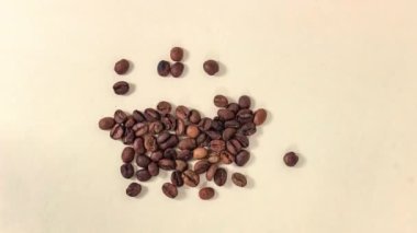 Hareket animasyonunu durdur. Çizgi film. Kavrulmuş kahve çekirdekleri fincana dönüşüyor ve içkiden buhar çıkıyor. Üst görünüm.