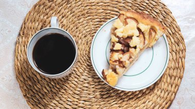 İçinde Charlotte 'un bir parçası olan bir fincan tabağı olan sıcak sade kahve. Üst görünüm.