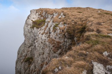 Kuru Dağ 'da (Suva planina) kayalık, dik kayalık, sonbaharda kuru, turuncu çimlerle kaplı ve bulutlu mavi gökyüzü