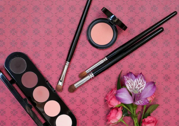 Makyaj kozmetik, fırçalar, shadoes ve çiçekler kırmızı zemin üzerine kompozisyonu