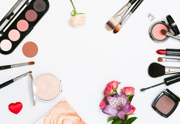 Makyaj kozmetik, fırçalar, shadoes ve beyaz arka plan üzerinde çiçekler ile kompozisyon