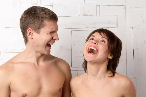 Young couple with emotions of laughtering near the white wall — Stock Photo, Image