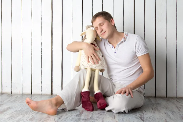 Man with toy goat sitting near the wall — Stock Photo, Image