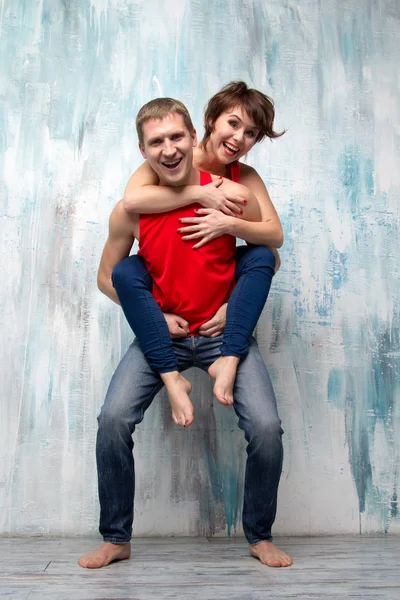 Woman sits on man's back near the wall — Stock Photo, Image