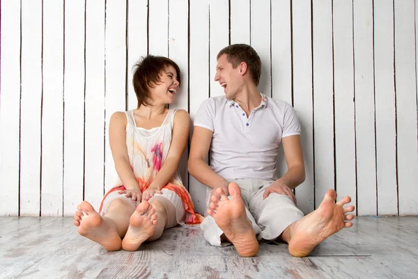 Young couple is laughing near the white wooden wall — Stock Photo, Image