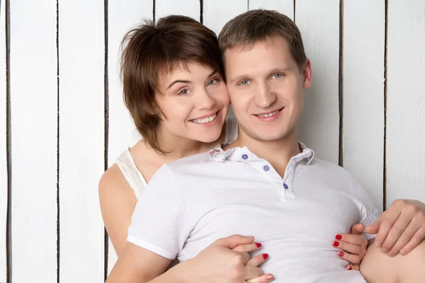 Young couple is sitting near the white wooden wall — Stock Photo, Image