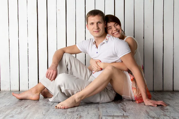 Young couple is sitting near the white wooden wall — Stock Photo, Image