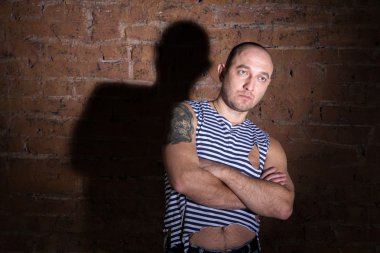 Dövme ayakta tuğla duvarın yanında ciddi kel adam