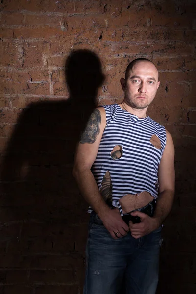 Serious bald man with tattoo standing near the brick wall — Stock Photo, Image