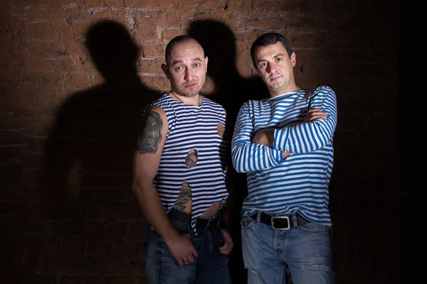 İki acımasız adam tuğla duvara yakın duran