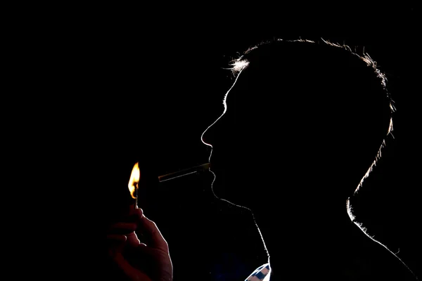 Karanlıkta sigara yakıyor adam silüeti