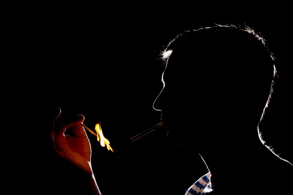 Silhouette de l'homme qui allume la cigarette dans le noir — Photo
