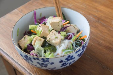 İçinde tofu, kırmızı lahana, marul, Wakame deniz yosunu ve havuç bulunan Vietnam eriştesi salatası. Bir kasede servis edildi..