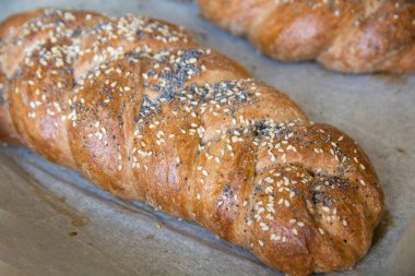 Geleneksel fırınlanmış Challah ekmeği, hecelenmiş undan yapılmış, susam ve haşhaş tohumlu.