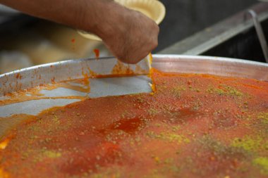 Man hand cutting a slice of Kanafeh, a traditional middle eastern delicious dessert, served in a white plate clipart