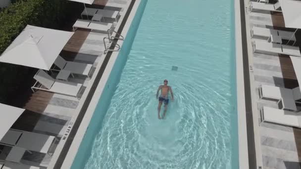 O jovem nada através da piscina. — Vídeo de Stock