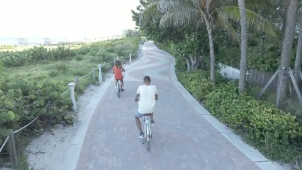 Dos amantes de andar en bicicleta a lo largo de la costa Miami Beach — Vídeos de Stock