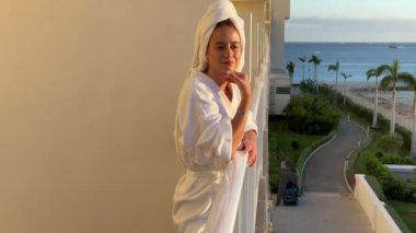 Güzel bayan balkonda gün batımını seyrediyor.