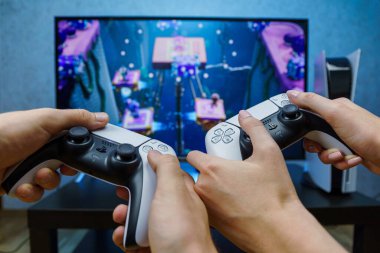 Sony PlayStation 5. Yeni nesil oyun bilgisayarı. Video oyunu oynayan insanlar. Çift PS5 ile oynuyor. Bakış açısı.